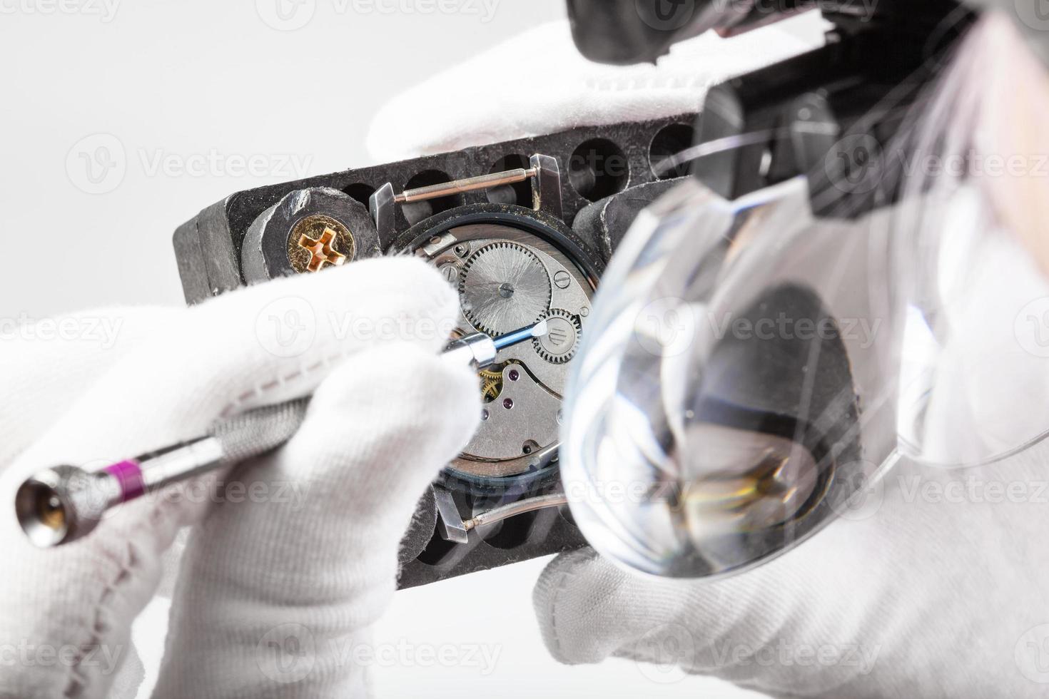 watchmaker in head magnifier repairs wristwatch photo