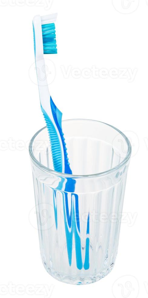 un cepillo de dientes azul en vidrio aislado en blanco foto