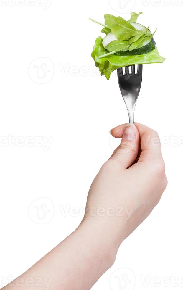 fork with impaled fresh green salad in hand photo