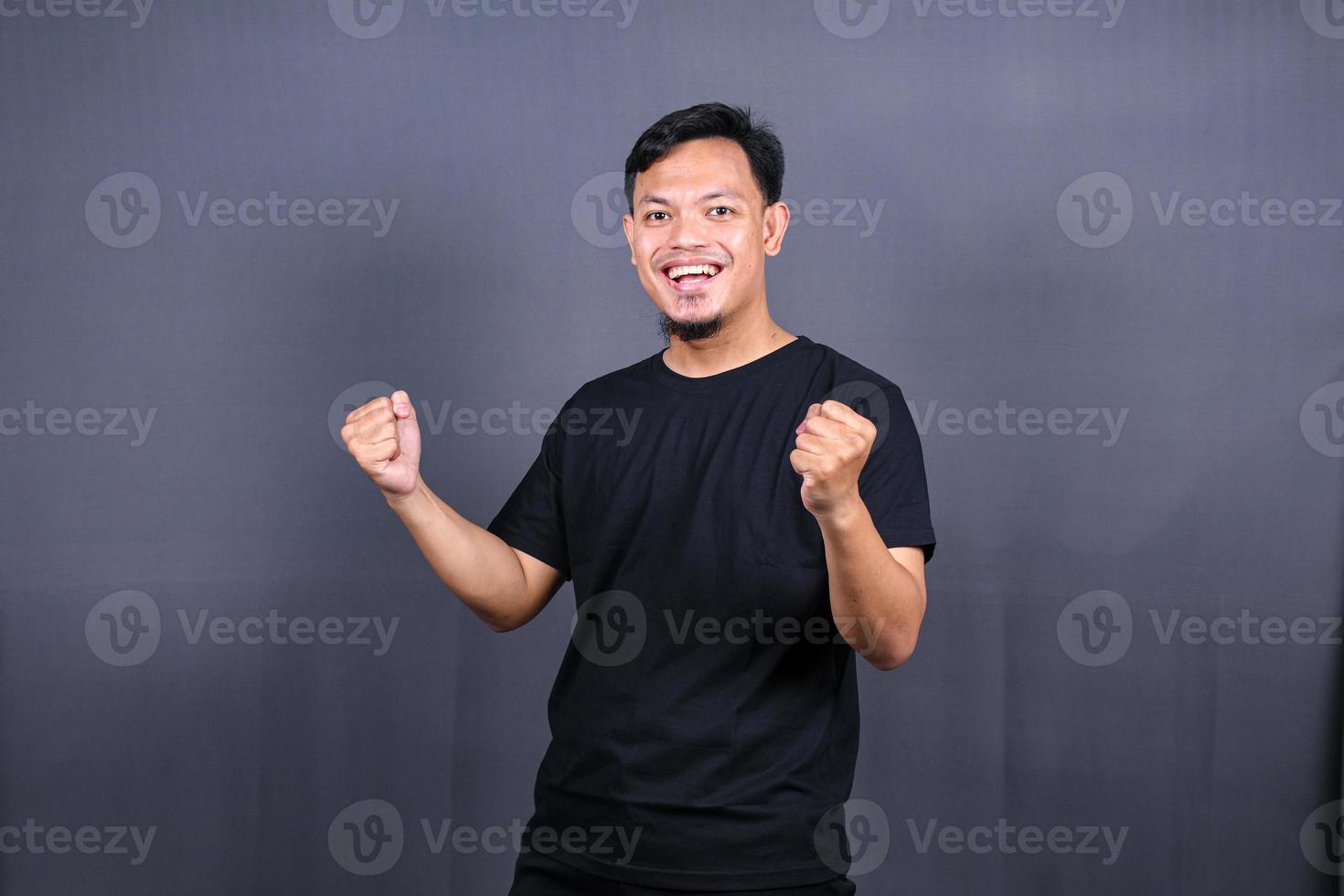 Amazed excited young asian man looking at camera with wow face expression feeling surprised advertising shopping promotion, unbelievable win standing isolated on gray background. photo