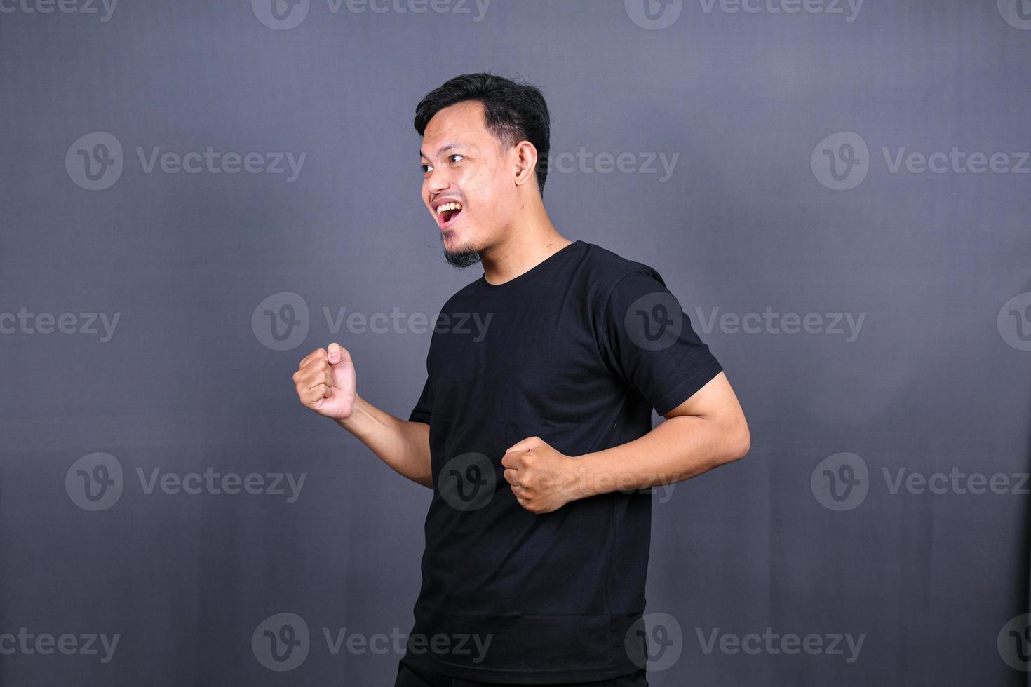 Amazed excited young asian man looking at camera with wow face expression feeling surprised advertising shopping promotion, unbelievable win standing isolated on gray background. photo