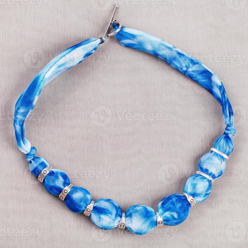 top view of necklace from blue silk balls on gray photo