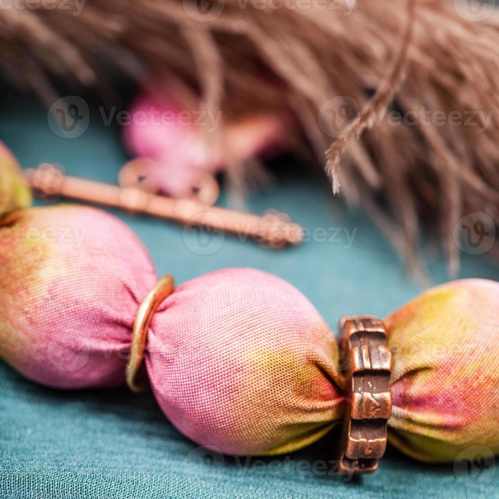 necklace from pink silk balls close up on green photo