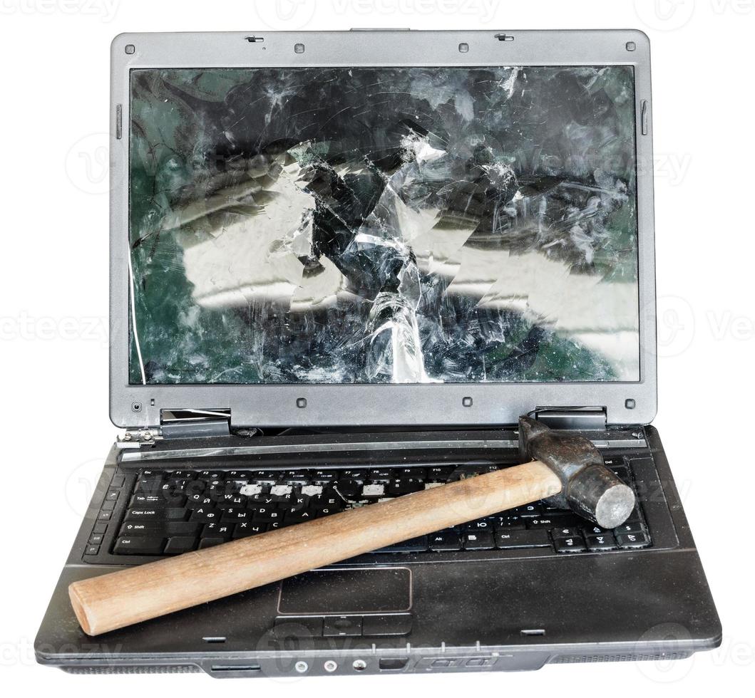 direct view of old broken laptop with hammer photo