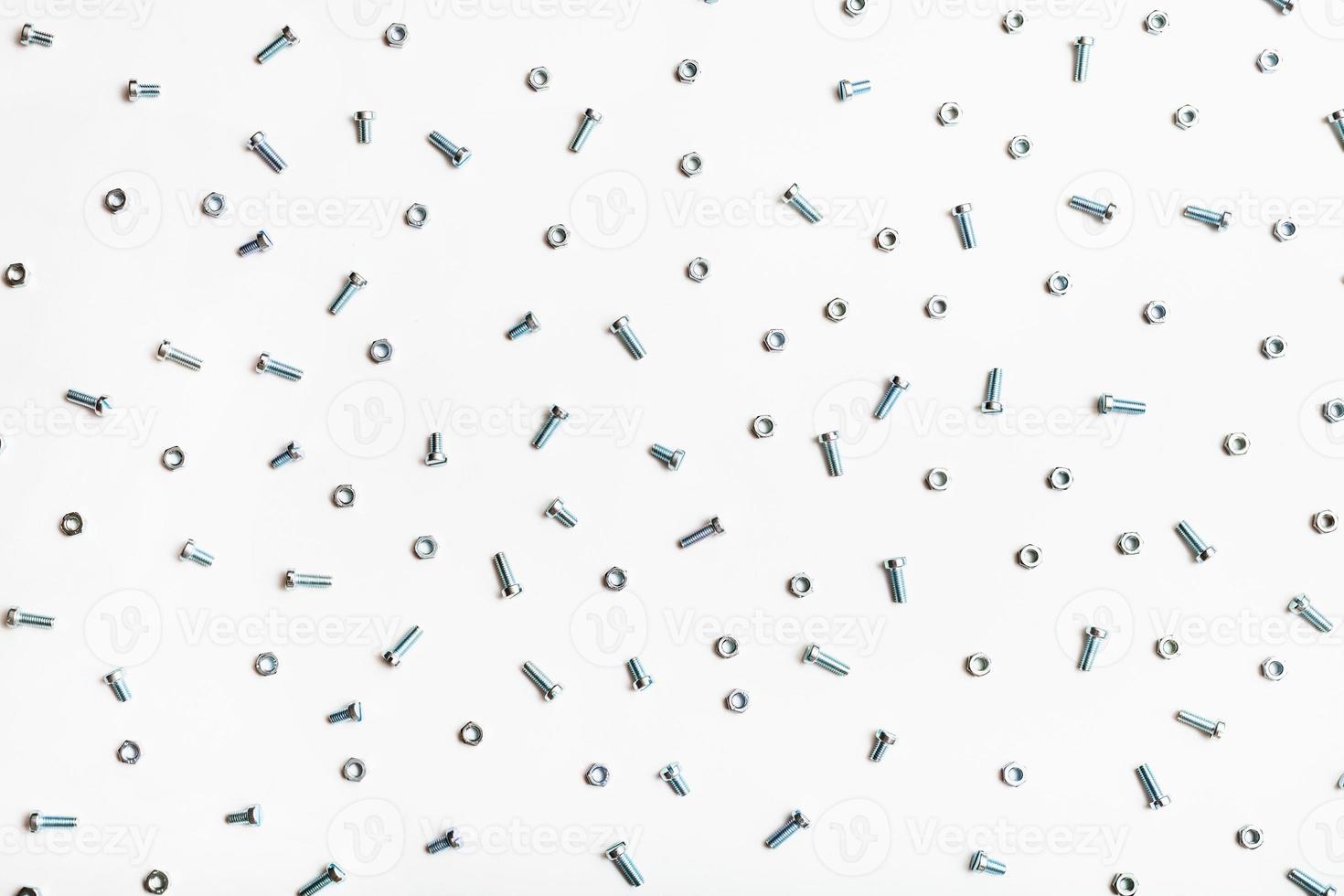 top view of many steel bolts and nuts on white photo