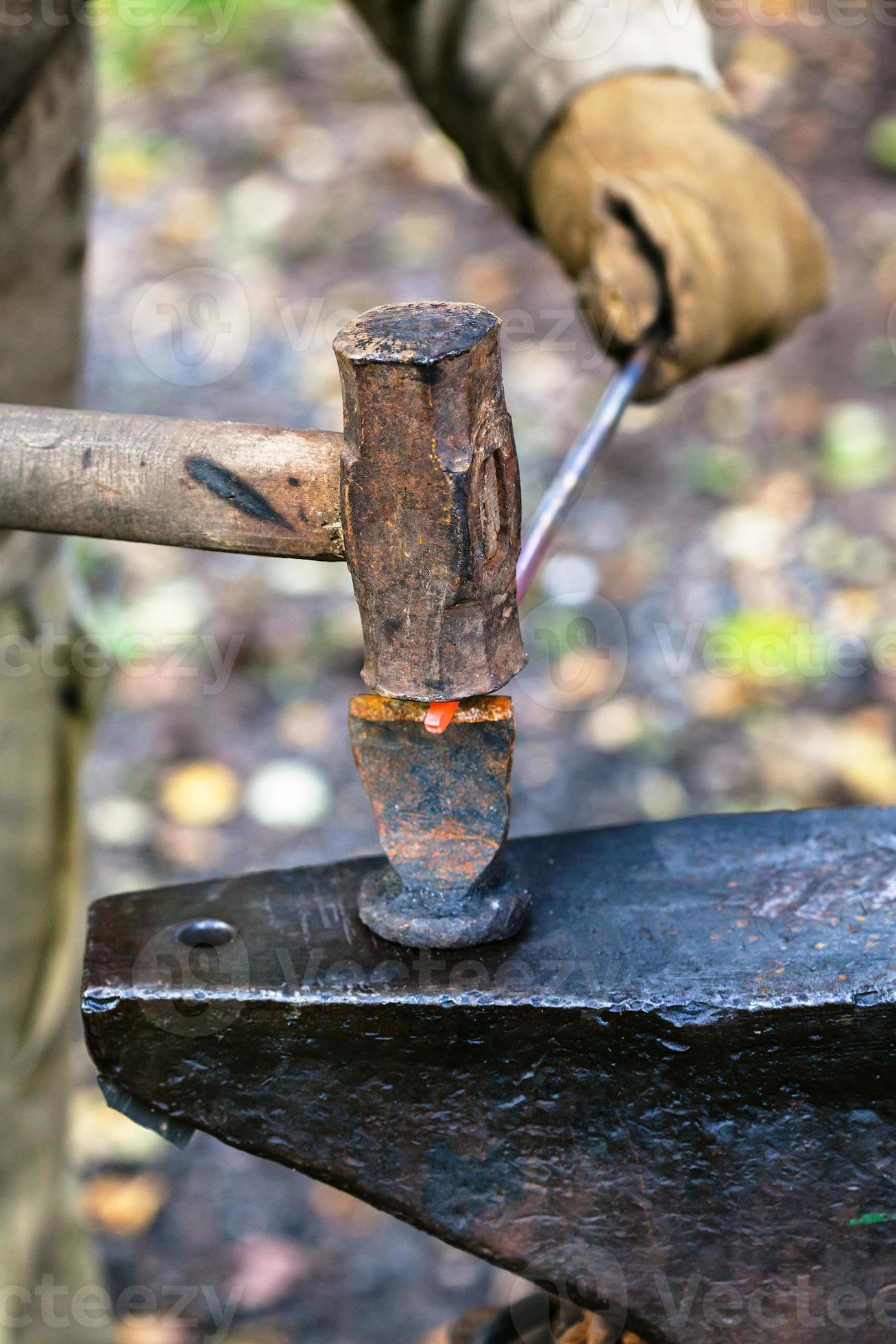 Blacksmith chops rod with sledgehammer and chisel 12575881 Stock Photo