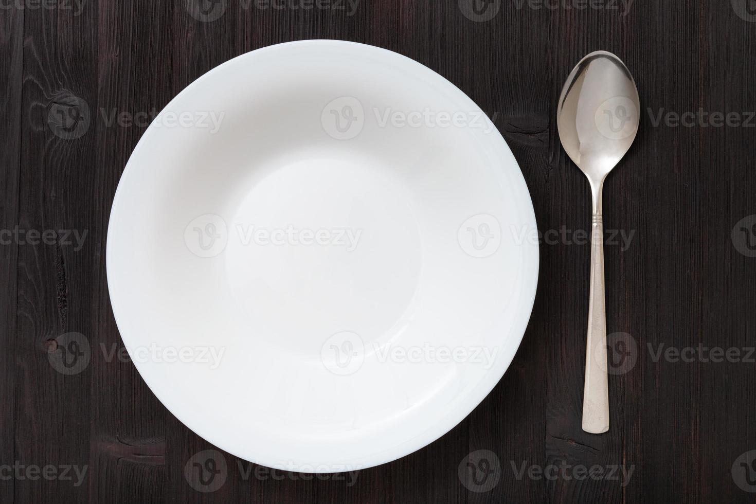 top view deep plate with spoon on dark brown table photo