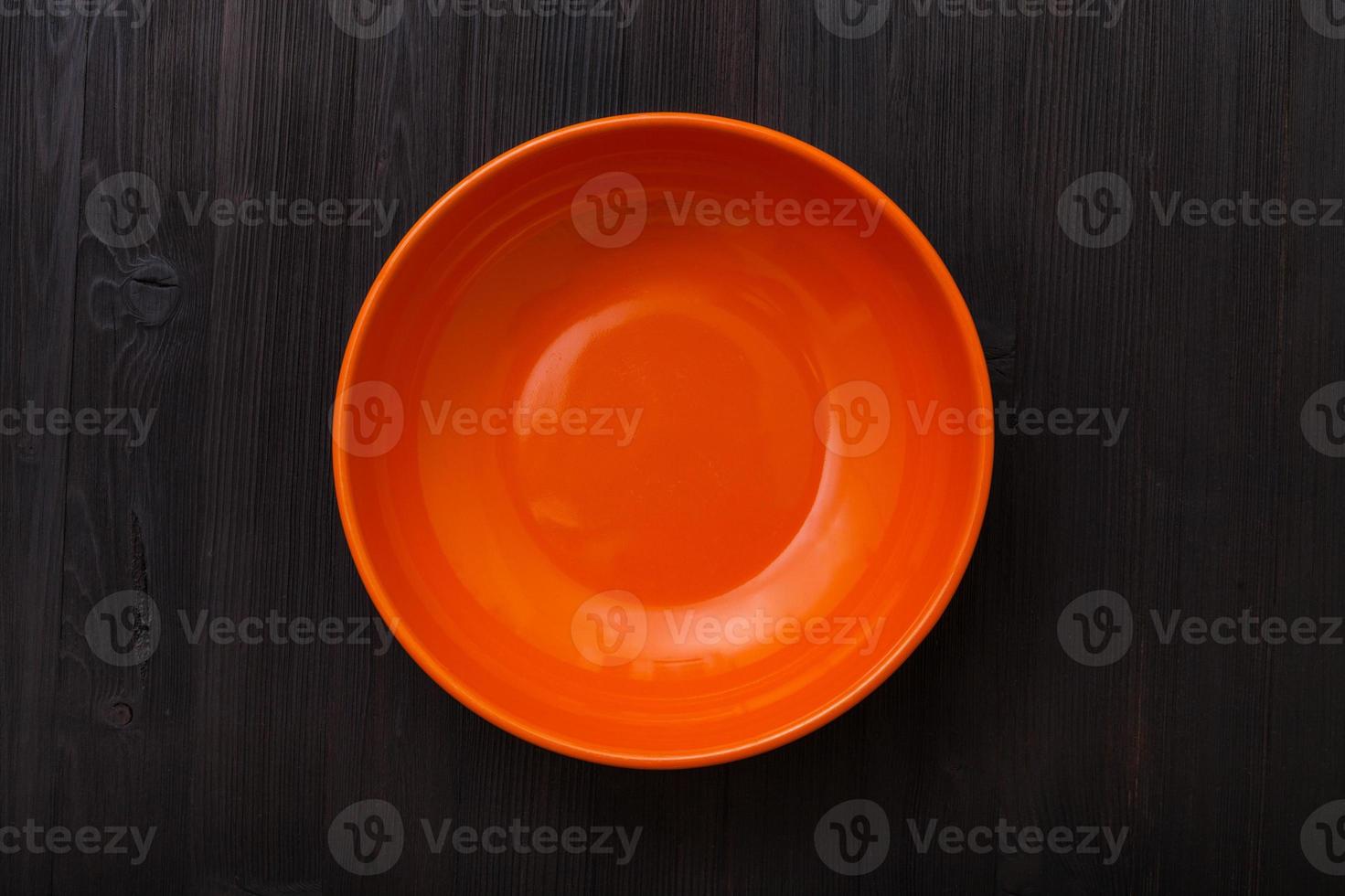 top view of orange bowl on dark brown table photo