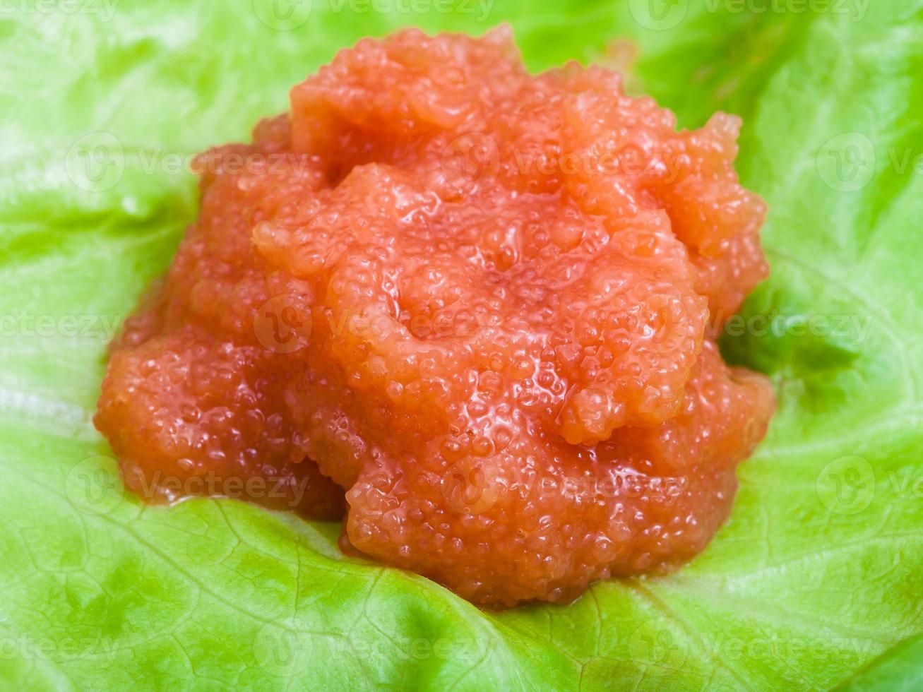 portion of salty caviar of whitefish on green leaf photo