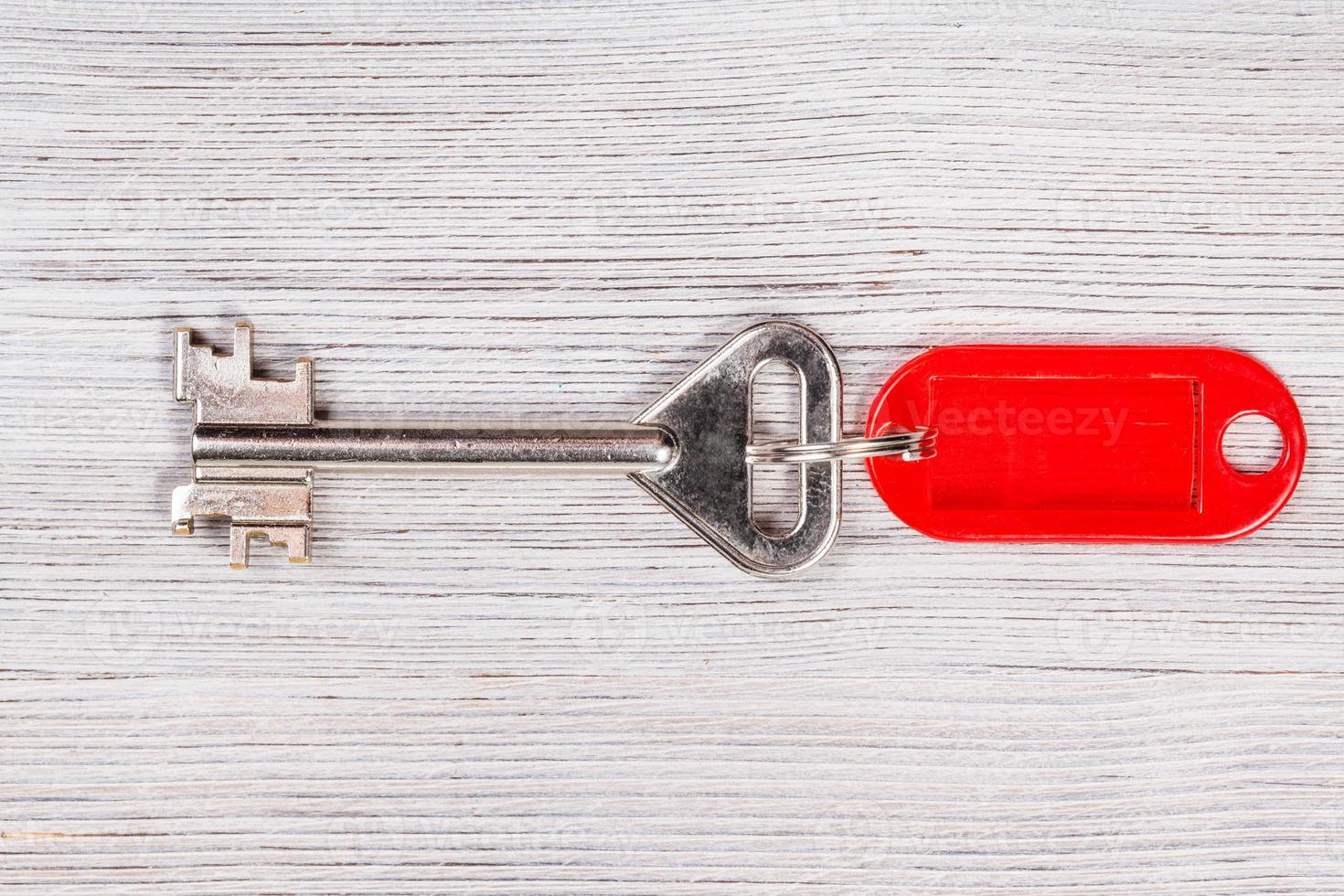 big door key with red keychain on wooden table photo