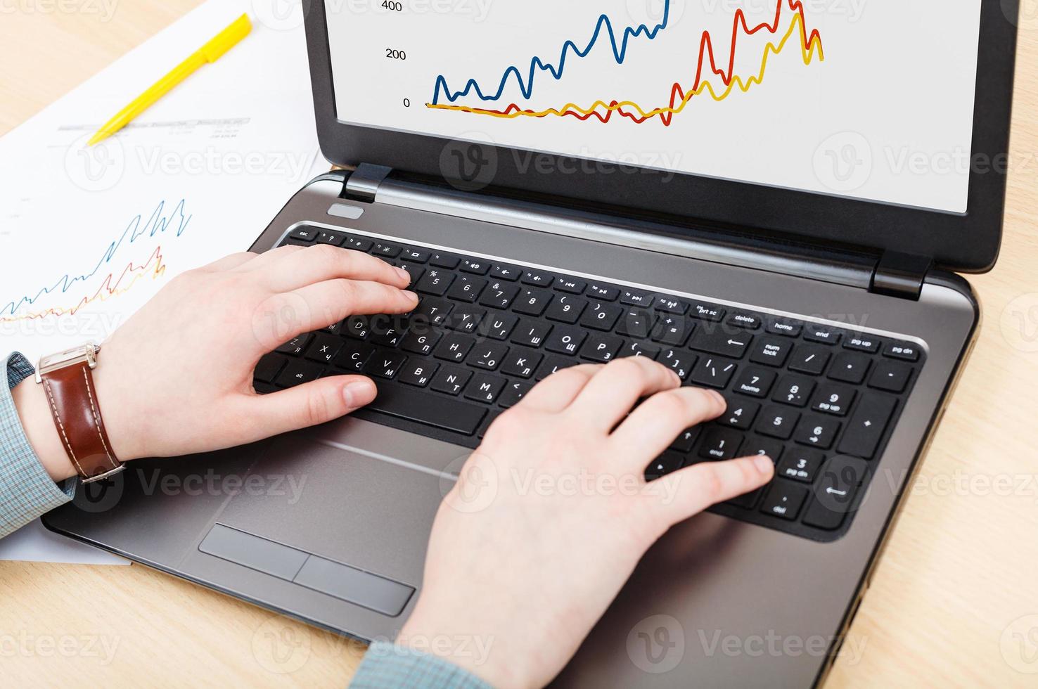 working with laptop and graph on screen at table photo