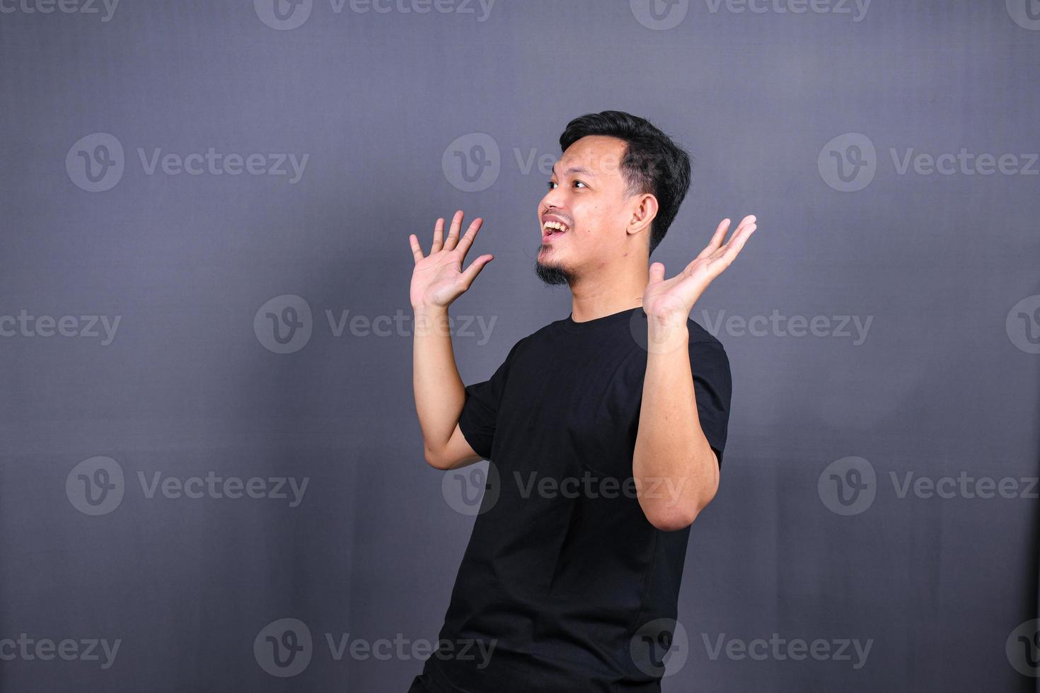 Amazed excited young asian man looking at camera with wow face expression feeling surprised advertising shopping promotion, unbelievable win standing isolated on gray background. photo