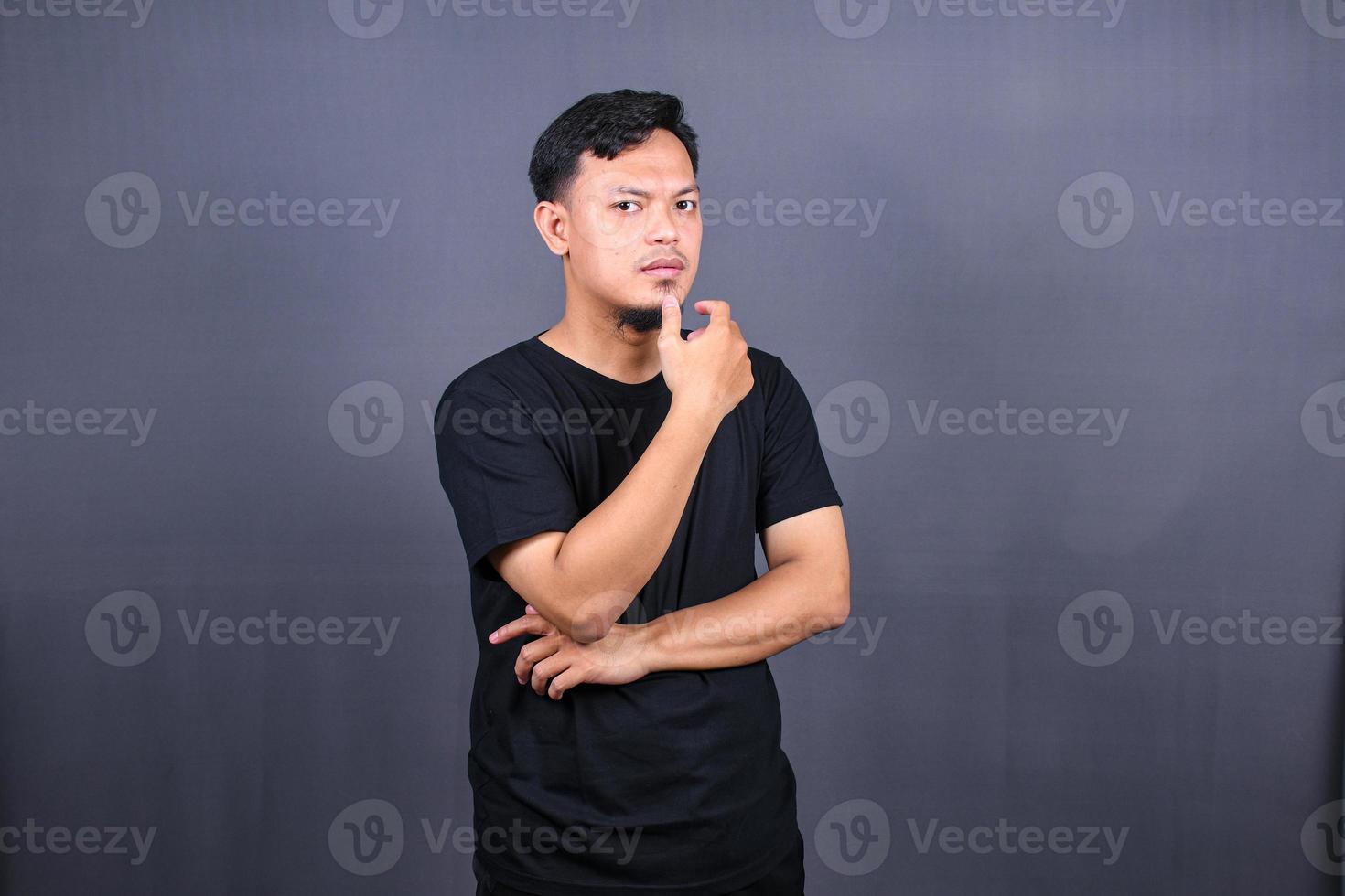 Asian young man thinking about things or idea wearing black t-shirt. Isolated gray background photo