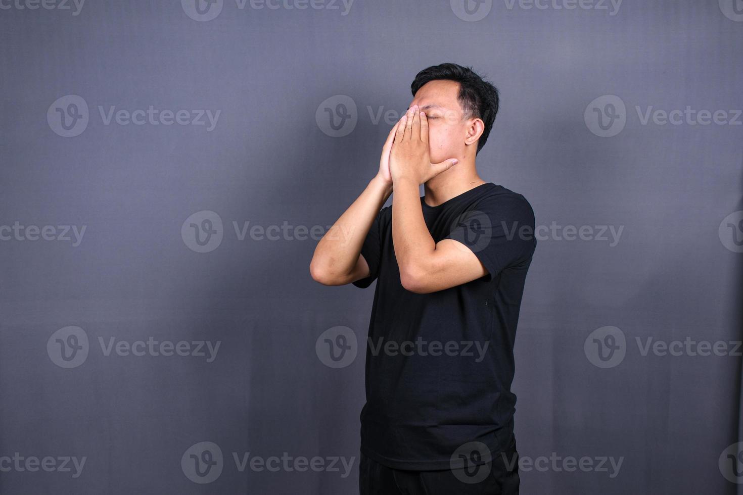 sad man with hands on face in sadness, isolated on gray background, copyspace photo