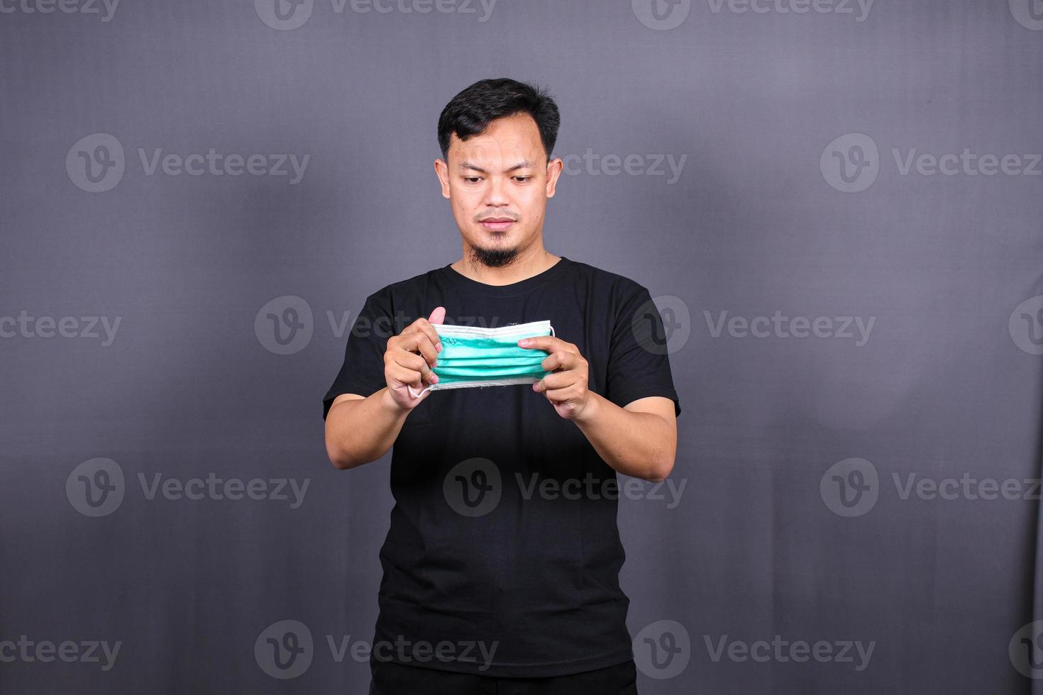 Asian man wearing a mouth protection or mask to prevent getting sick at work. Isolated on Gray Background photo