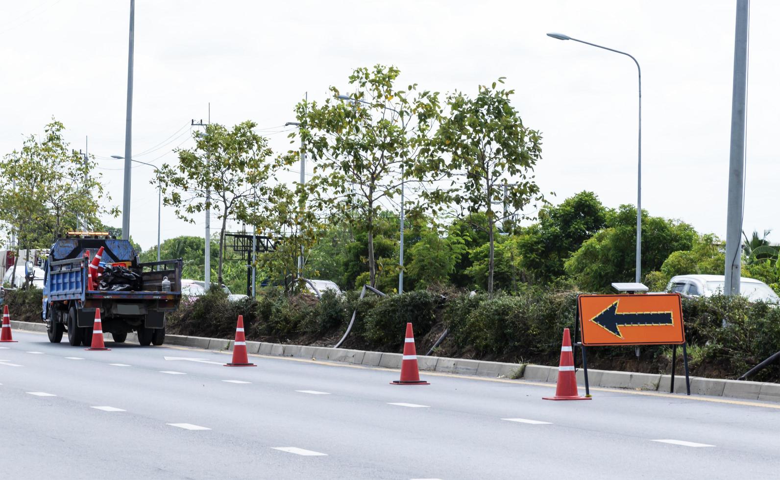 Orange traffic sign with arrow icon  and signal cones on highway photo