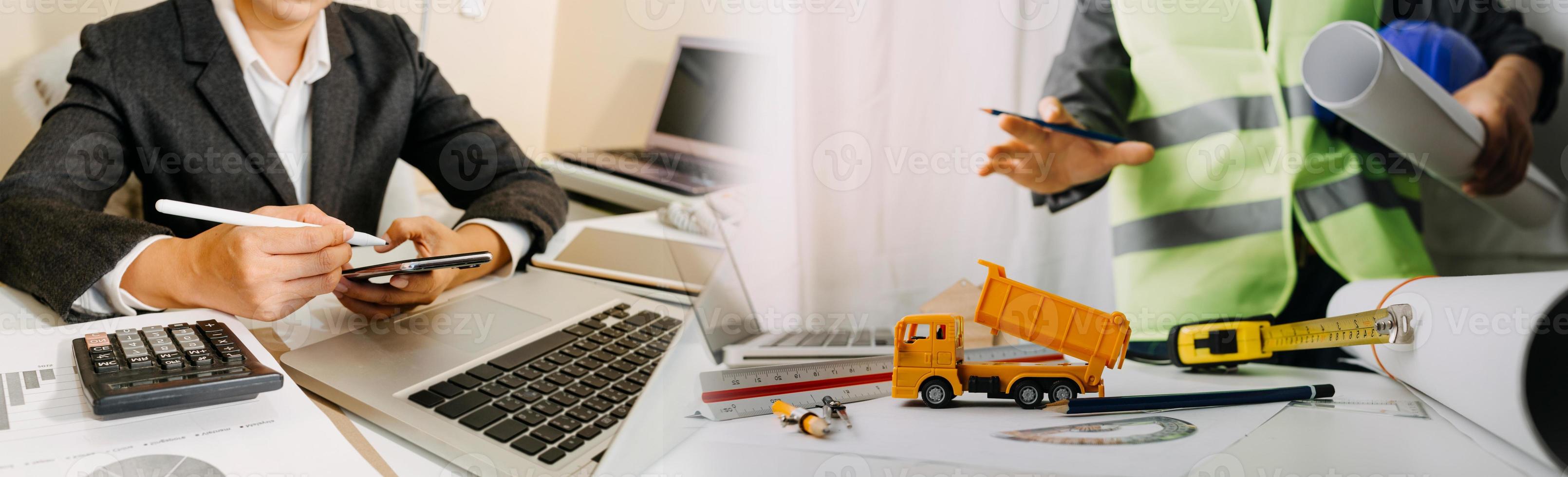 Two colleagues discussing data working and tablet, laptop with on on architectural project at construction site at desk in office photo