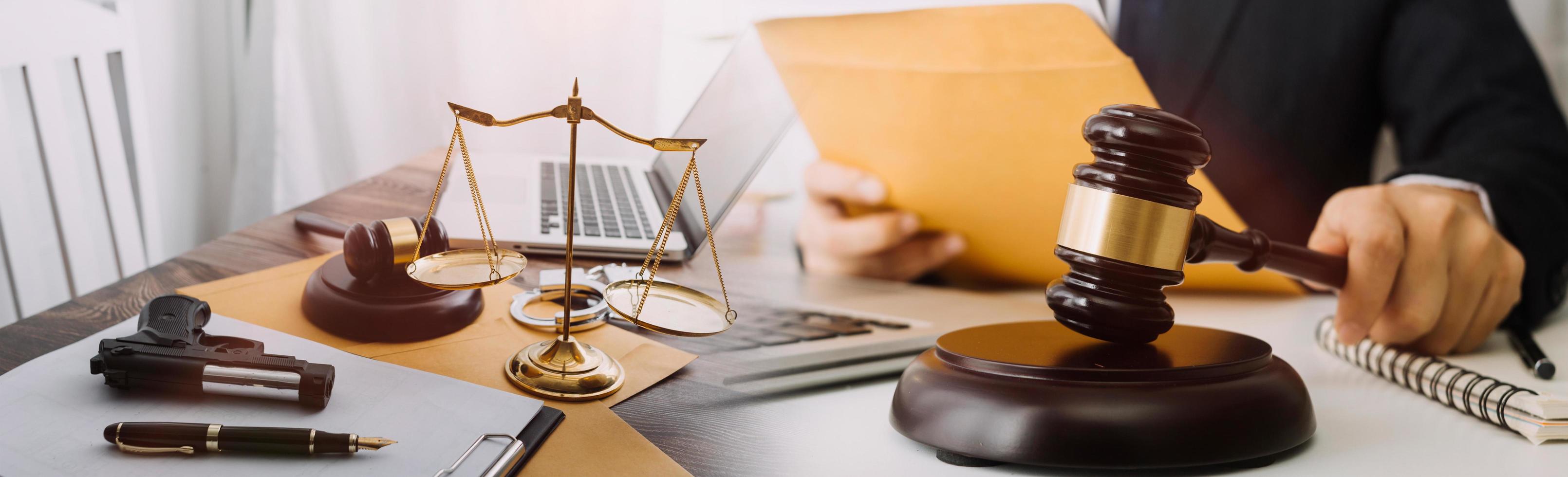 Justice and law concept.Male judge in a courtroom with the gavel, working with, computer and docking keyboard, eyeglasses, on table in morning light photo