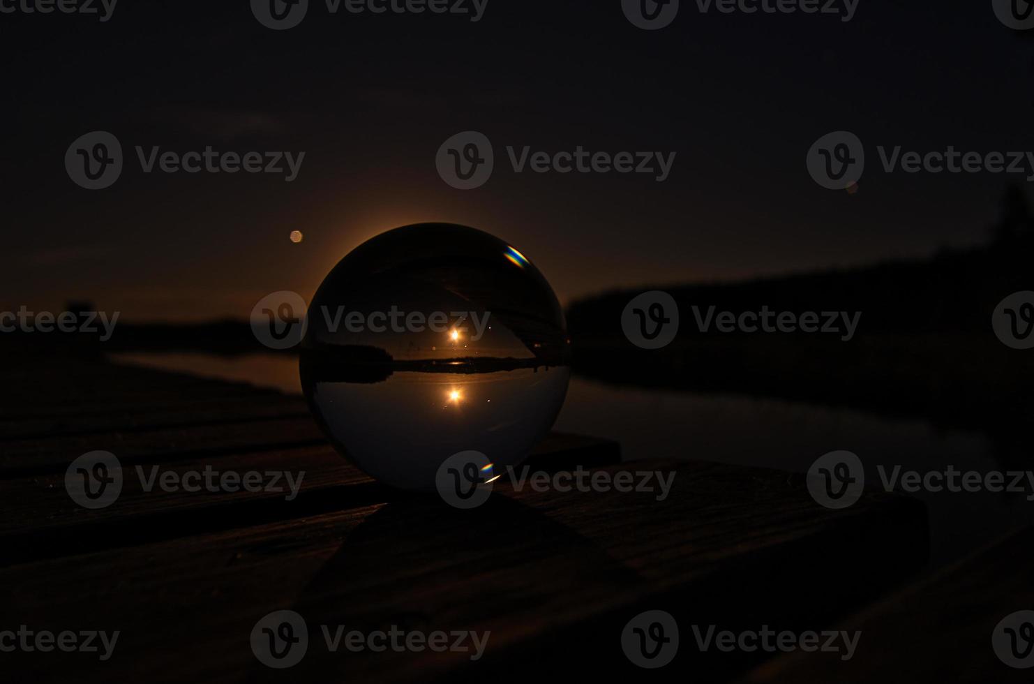 Glass ball on a wooden pier at a Swedish lake at night. Stars and moon photo