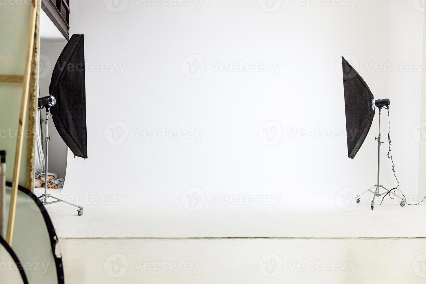 Empty photo studio with lighting equipment. Photographer workplace interior with professional tool set gear. Flash light white background scenes ready for studio shooting. Modern photographer studio