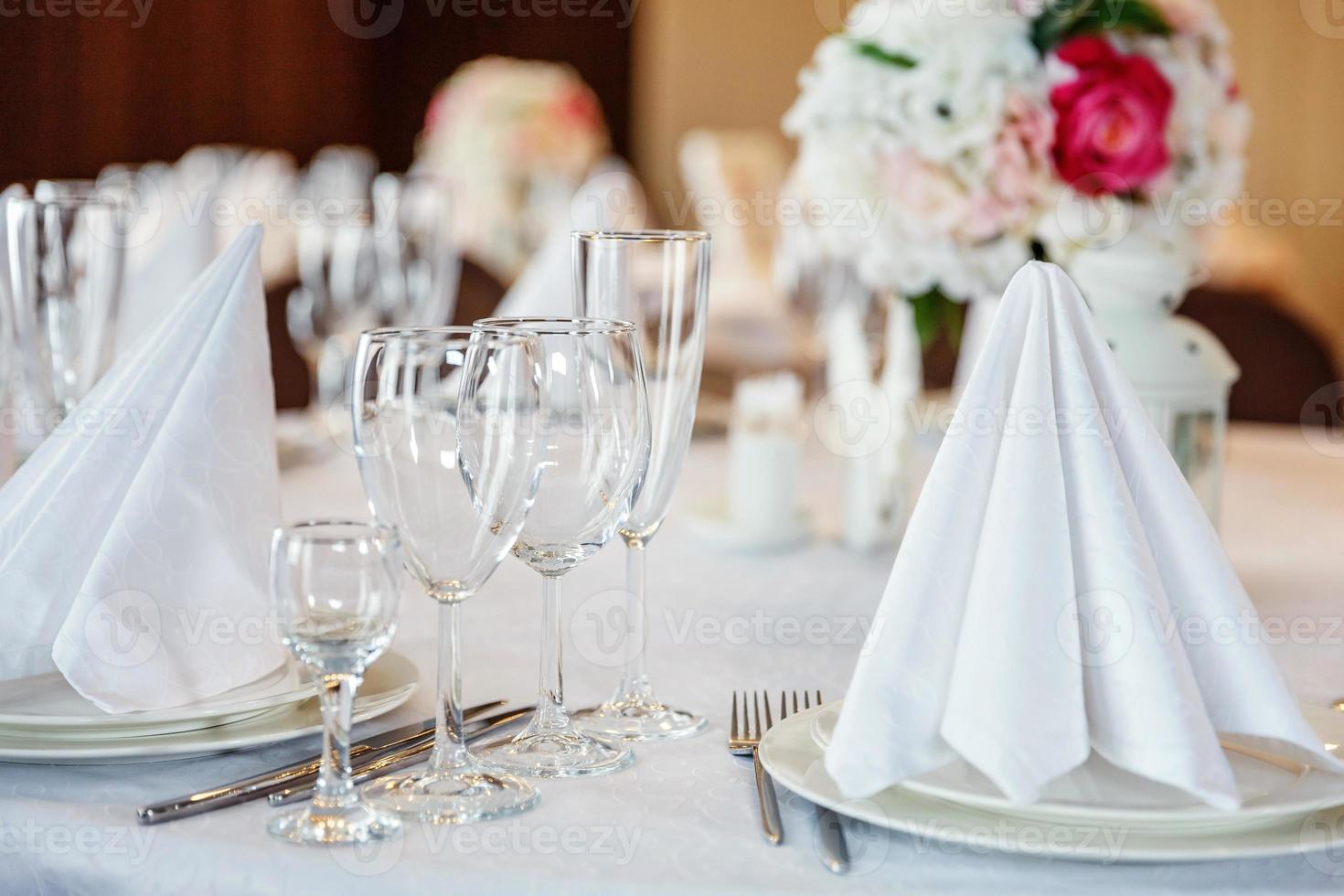 Fancy table set for dinner with napkin glasses in restaurant, luxury interior background. Wedding elegant banquet decoration and items for food arranged by catering service on white tablecloth table. photo