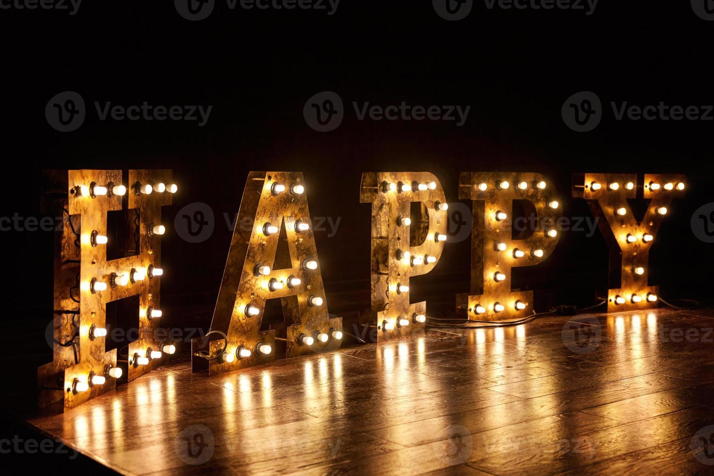 Happy letters word glowing light retro bulbs standing on floor. Modern dark classical style interior design apartment with retro lamps light bulbs background. Decorated interior room with gold lights. photo