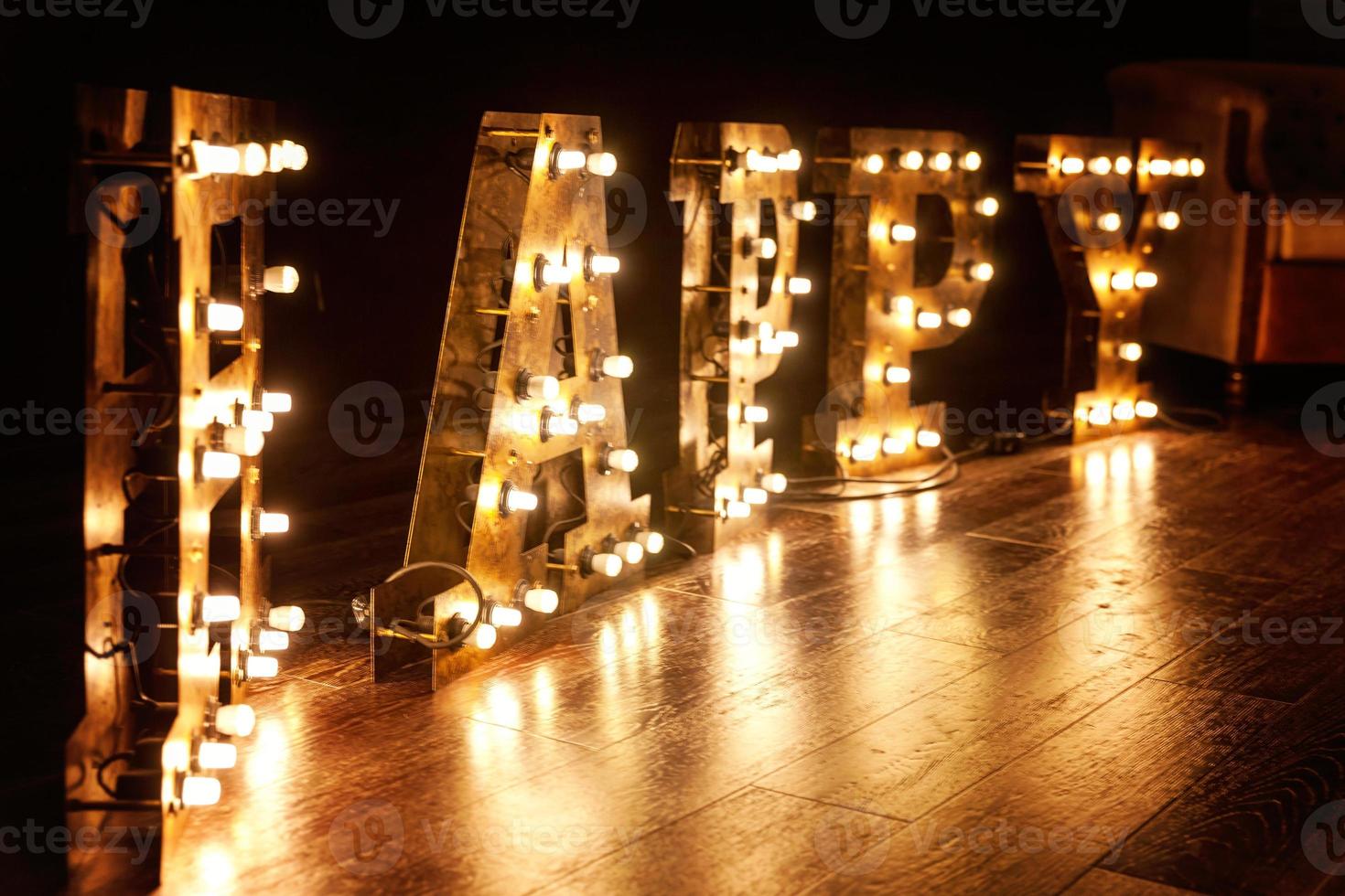 Happy letters word glowing light retro bulbs standing on floor. Modern dark classical style interior design apartment with retro lamps light bulbs background. Decorated interior room with gold lights. photo