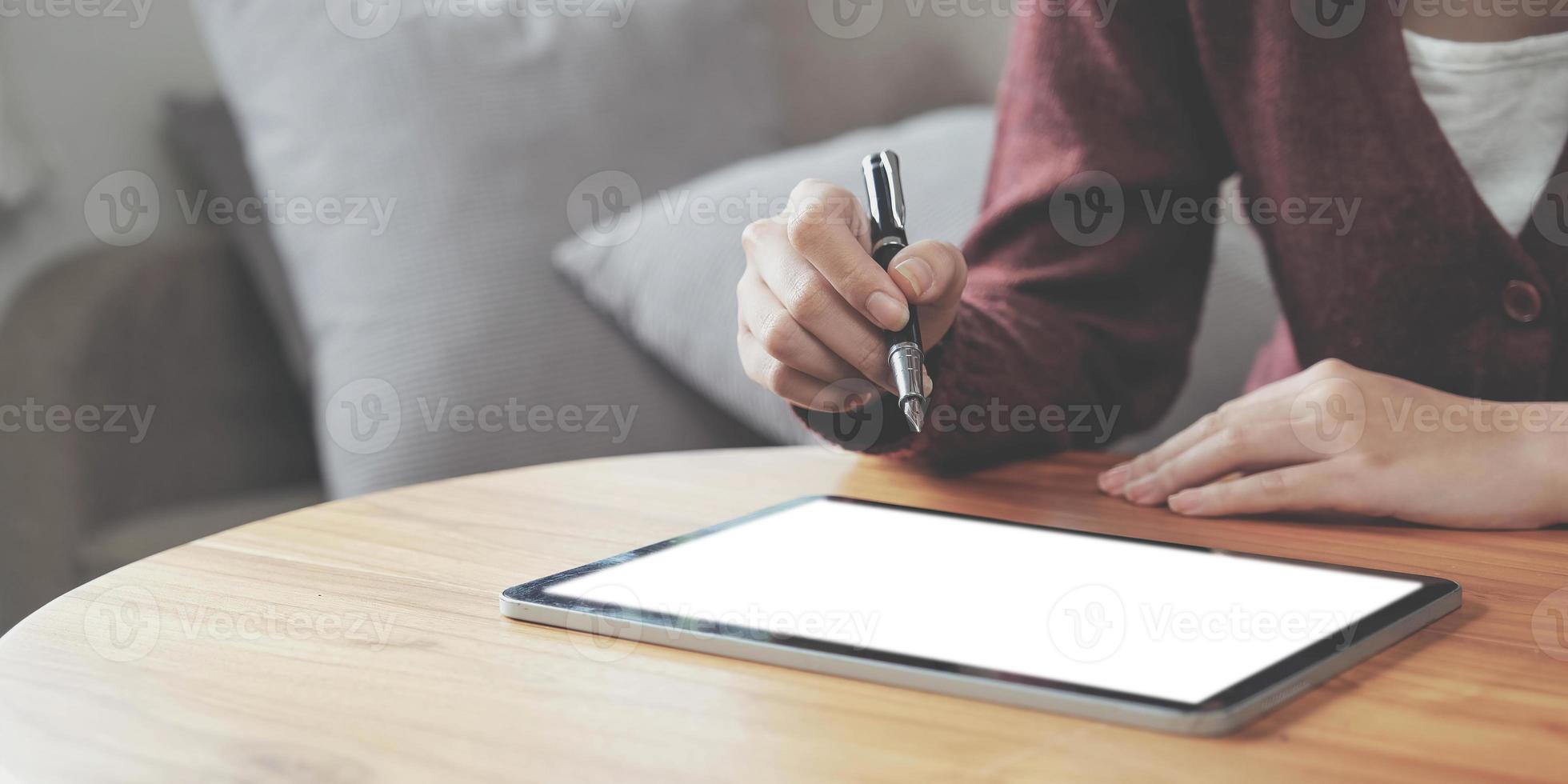 El primer plano de una mujer joven que usa tecnología de pluma inteligente para trabajar y escribir en la pantalla de una tableta digital foto