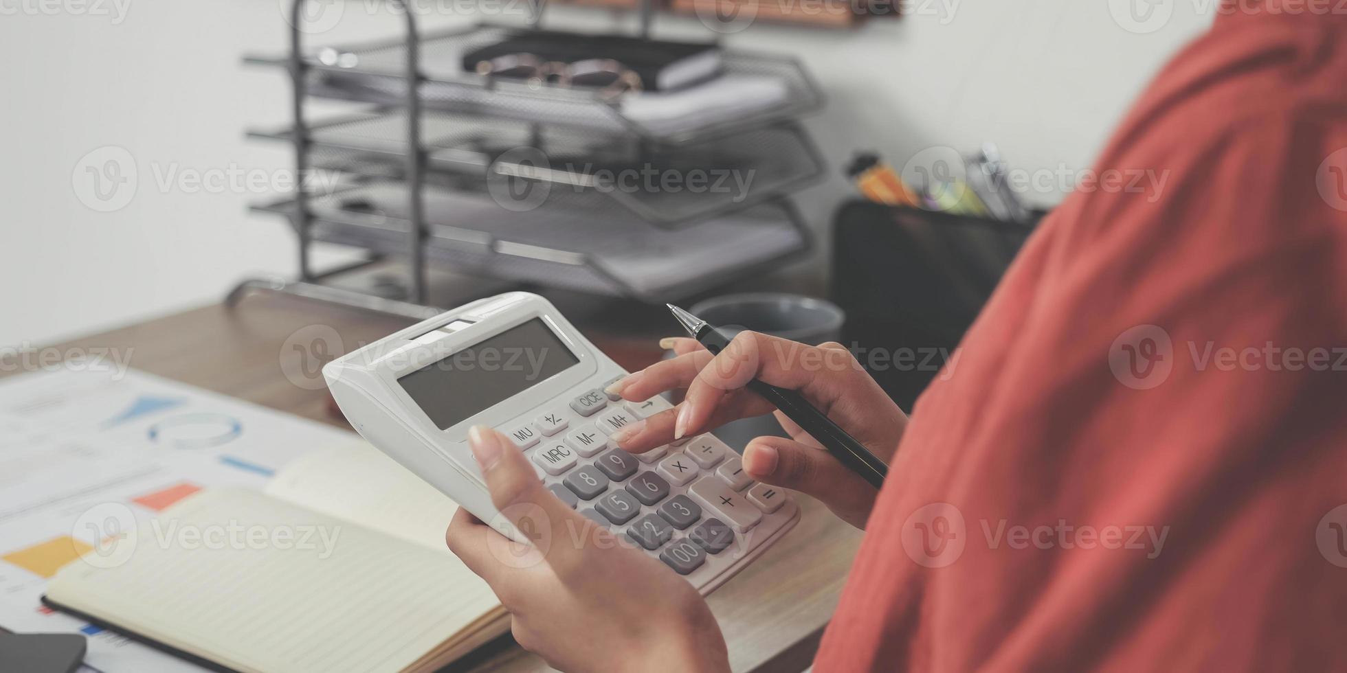 mujer de negocios que usa calculadora y computadora portátil para hacer finanzas matemáticas en un escritorio de madera en la oficina y el fondo de trabajo comercial, impuestos, contabilidad, estadísticas y concepto de investigación analítica foto