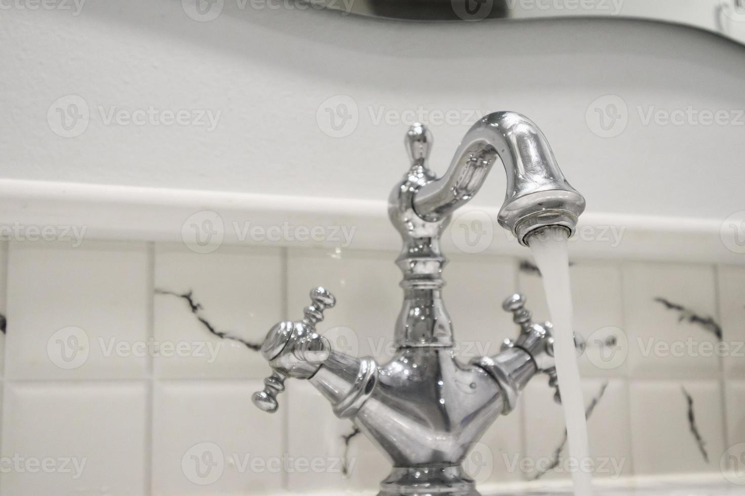 Water from vintage style faucet in the bathroom photo