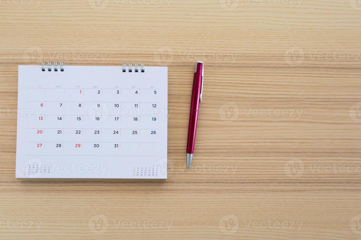 página de calendario con bolígrafo sobre fondo de mesa de madera foto