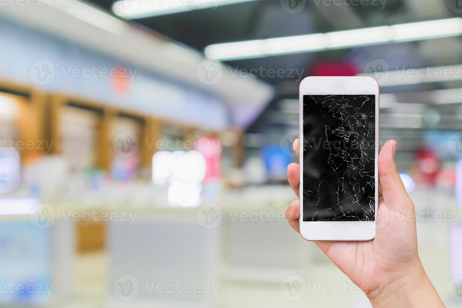 teléfono móvil de mano con pantalla de cristal rota con tienda electrónica de desenfoque abstracto para el concepto de reparación de teléfonos inteligentes foto