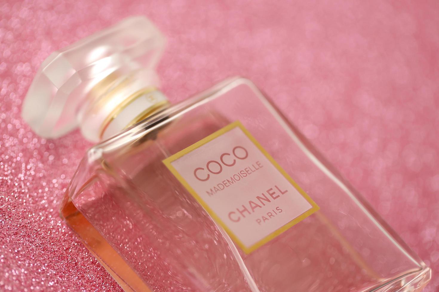 TERNOPIL, UKRAINE - SEPTEMBER 2, 2022 Coco Mademoiselle Chanel Paris worldwide famous french perfume bottle on shiny glitter background in purple colors photo
