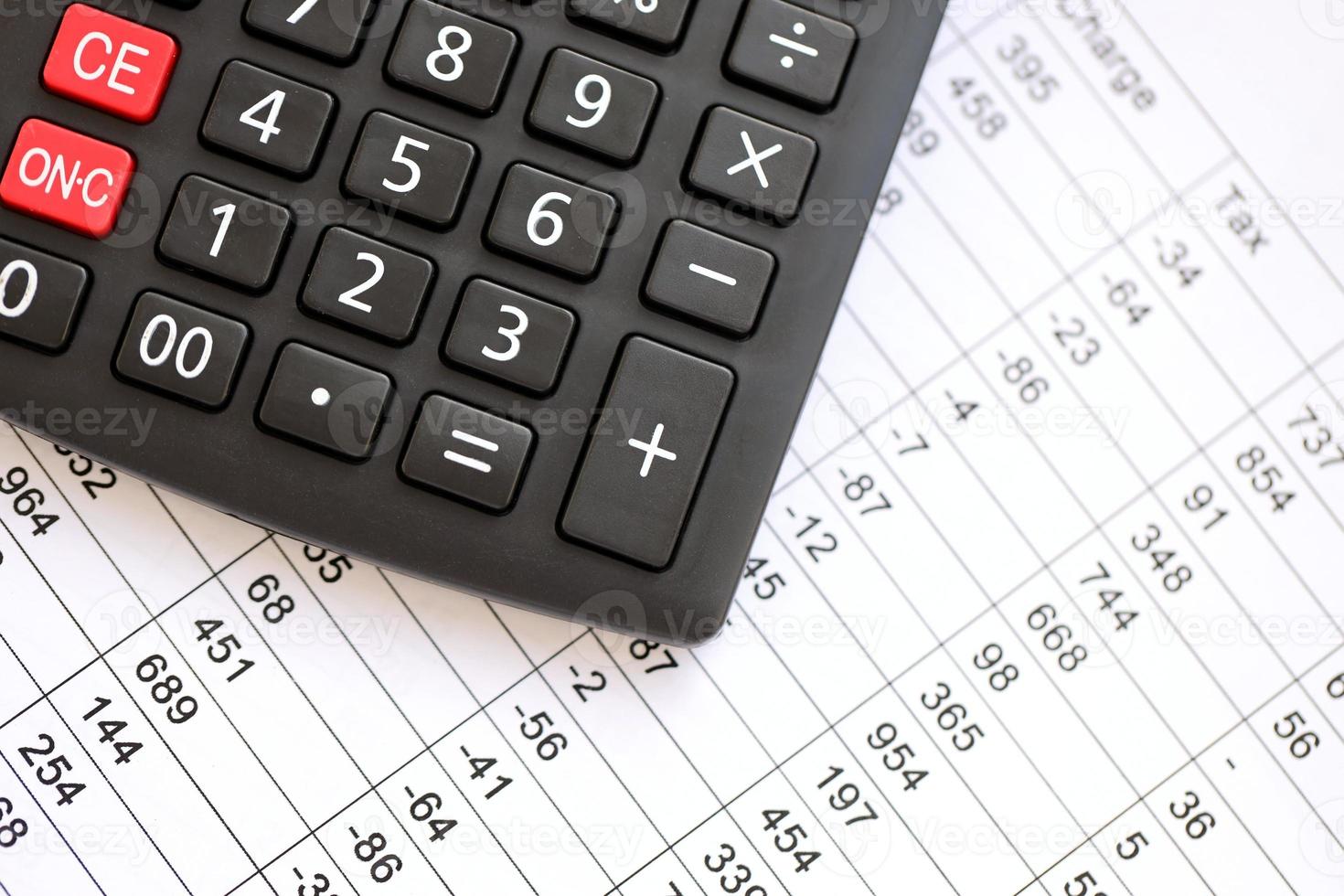 Big black calculator lies on financial statement and balance sheeet on desk of auditor close up. Concept of accounting and audit business. Taxpaying photo