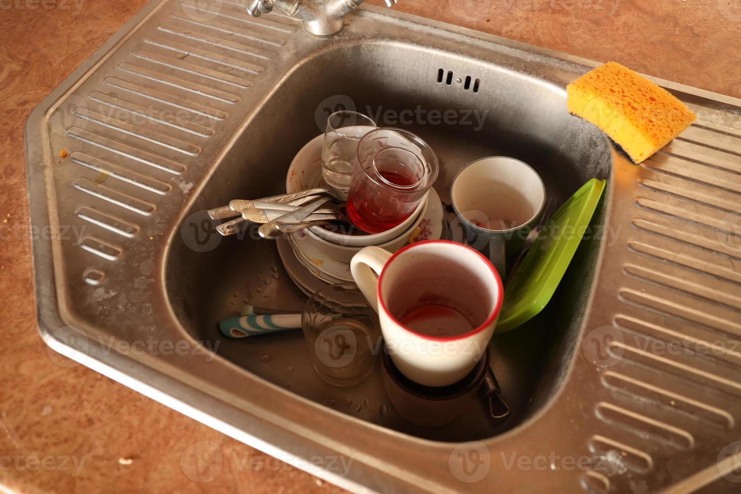 Stack of dirty dishes with food leftovers in the kitchen sink. Unwashed dishes photo