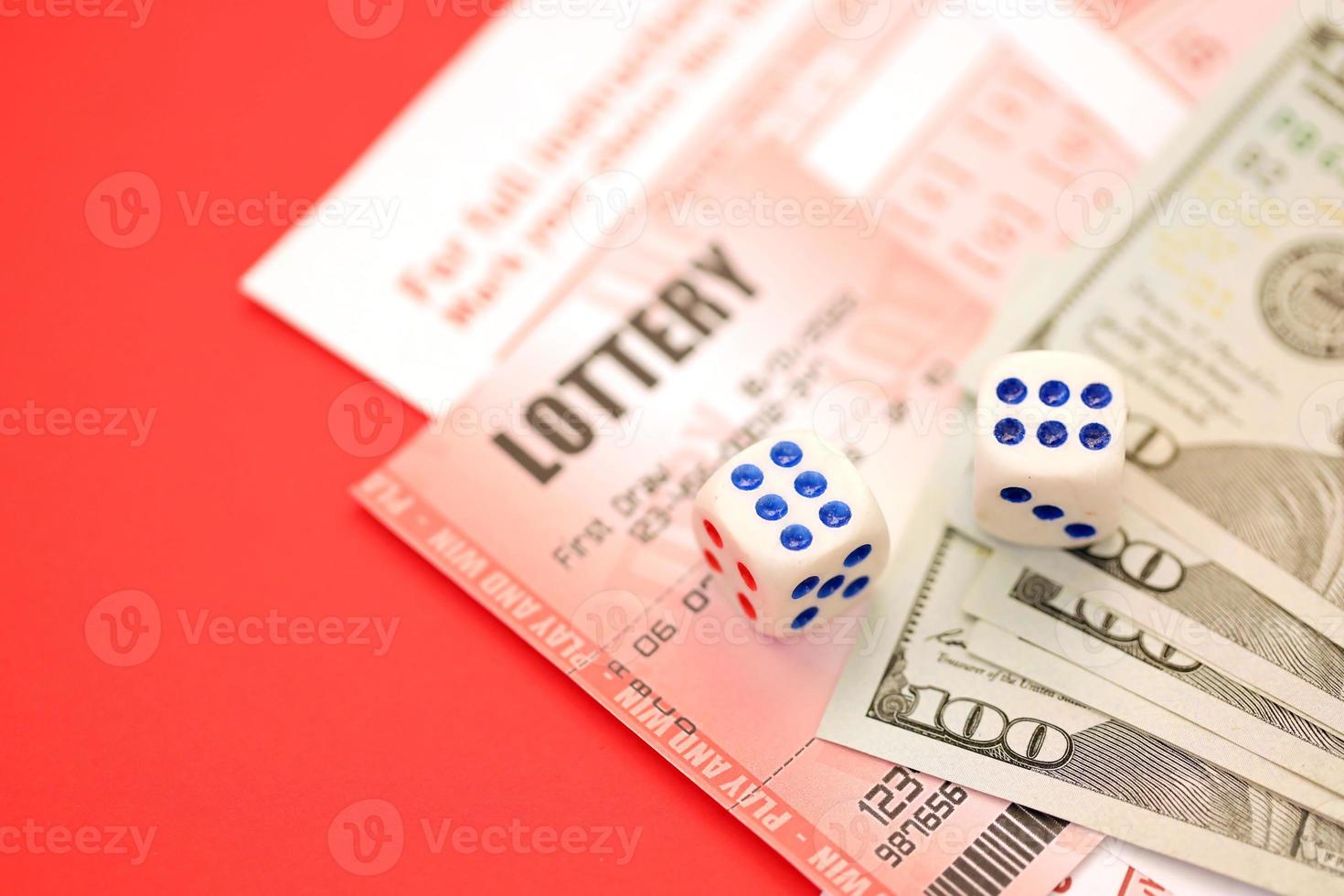 Red lottery ticket with dice and money lies on pink gambling sheets with numbers for marking to play lottery. Lottery playing concept or gambling addiction. Close up photo