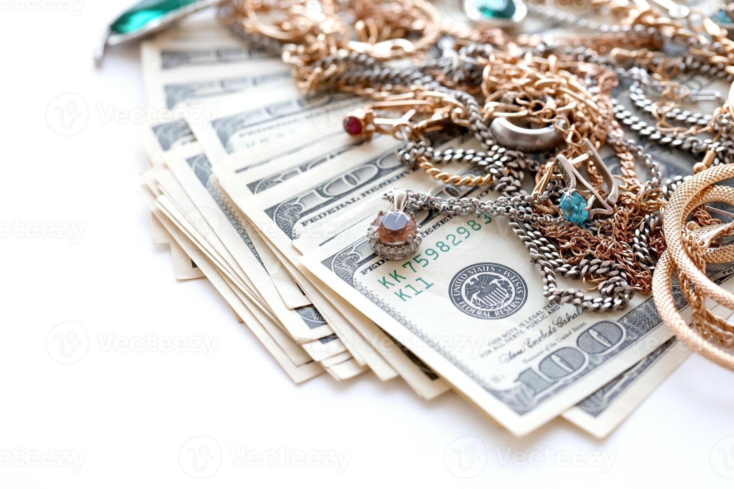 Many expensive golden and silver jewerly rings, earrings and necklaces with big amount of US dollar bills on white background. Pawnshop or jewerly shop photo