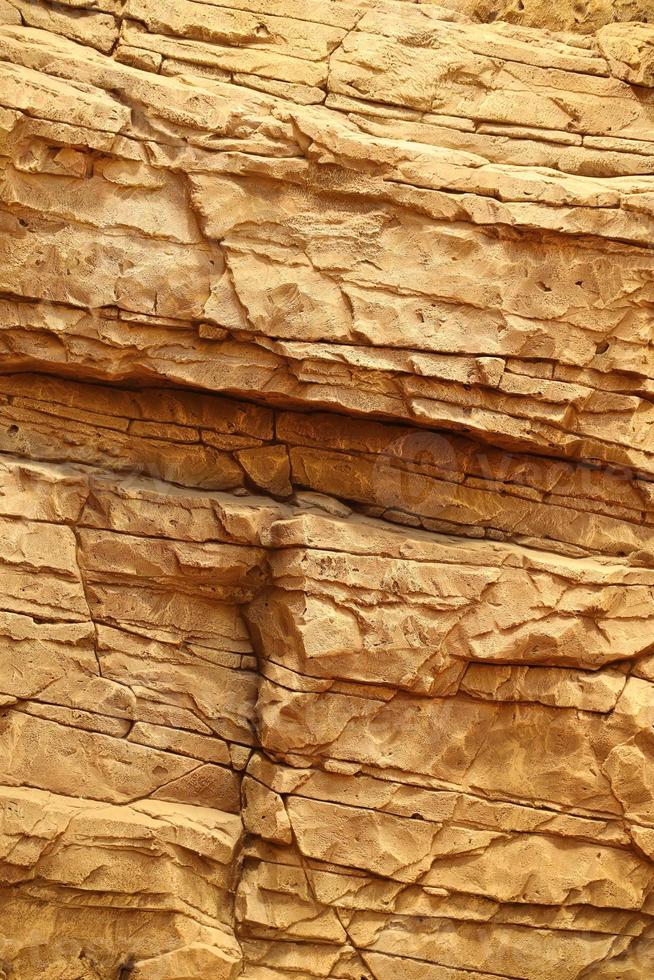 Light coarse natural rock stone background. Mining cliff rough front surface. Big limestone stack backdrop. Heavy grunge damaged granite block texture photo