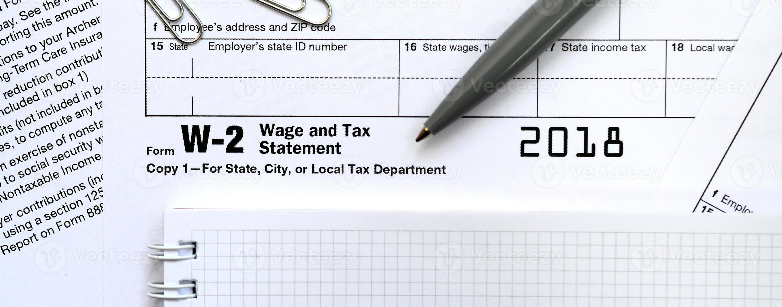 The pen and notebook on the tax form W-2 Wage and Tax Statement. The time to pay taxes photo