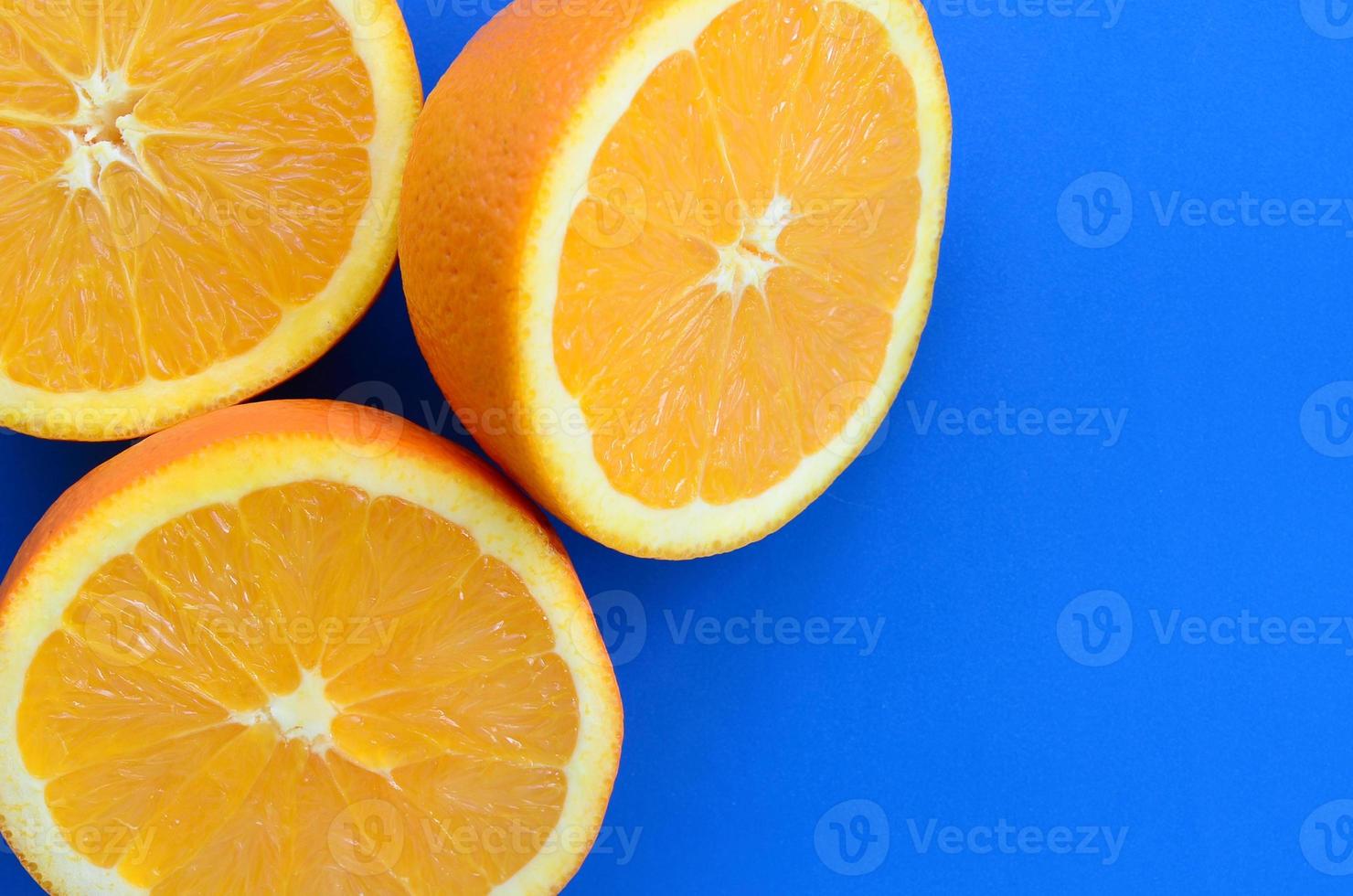 Top view of a several orange fruit slices on bright background in blue color. A saturated citrus texture image photo