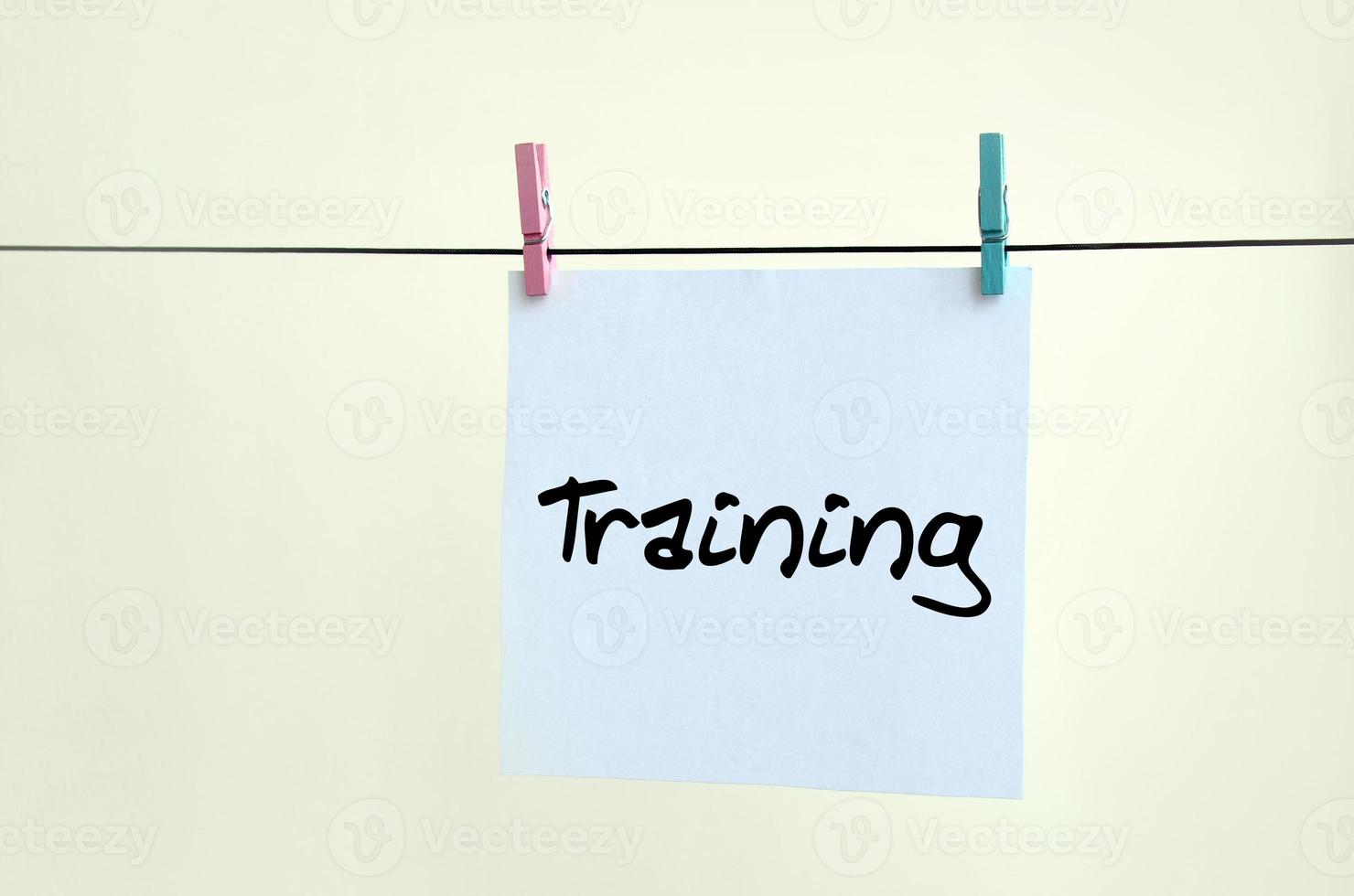 Training. Note is written on a white sticker that hangs with a clothespin on a rope on a background of beige wall photo
