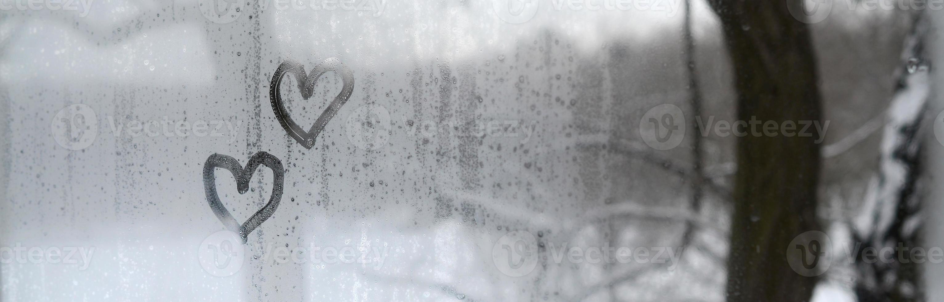 Two hearts painted on a misted glass in winter photo