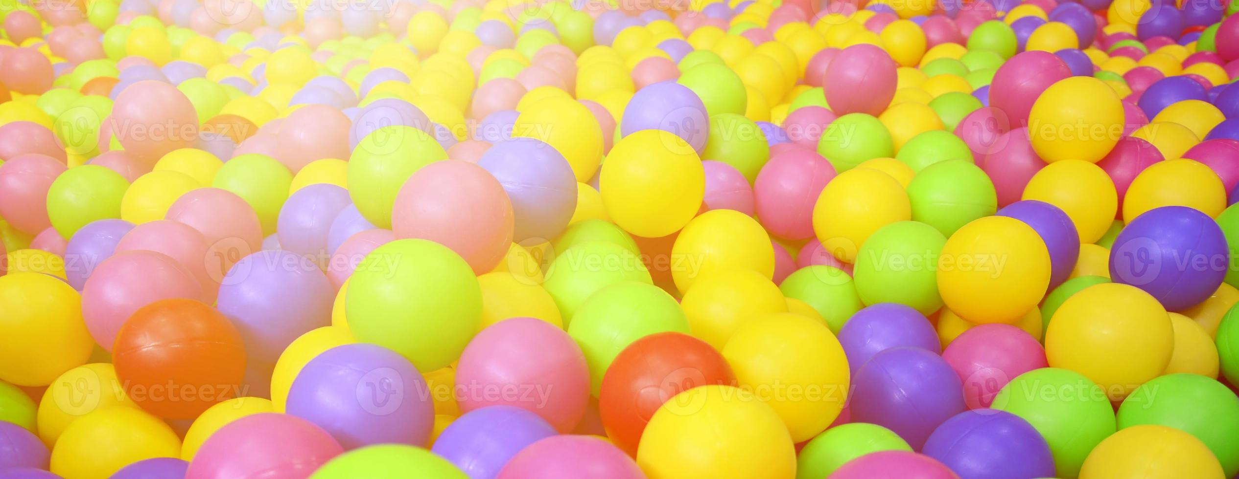 Many colorful plastic balls in a kids' ballpit at a playground. Close up pattern photo