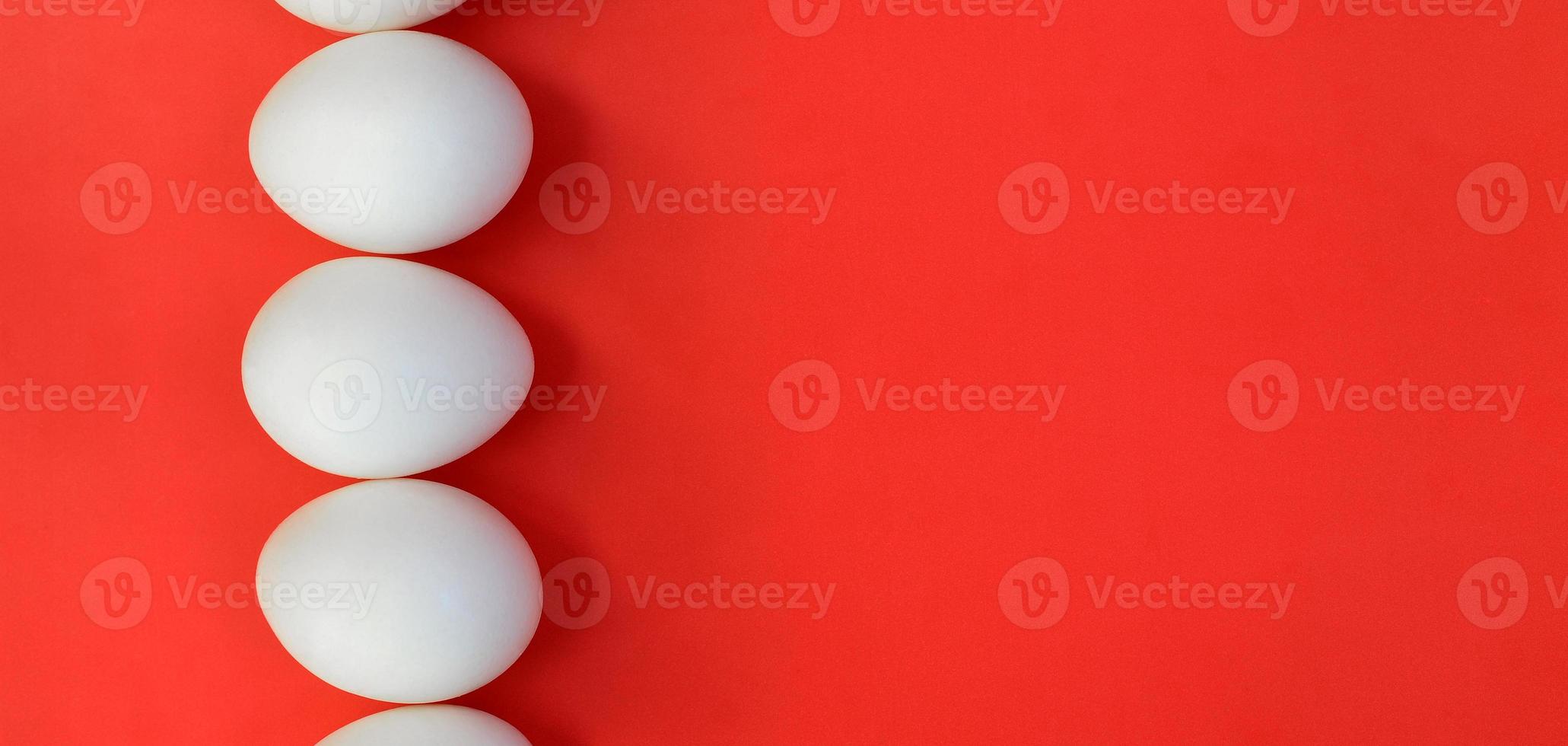 A few white eggs on a bright red background photo