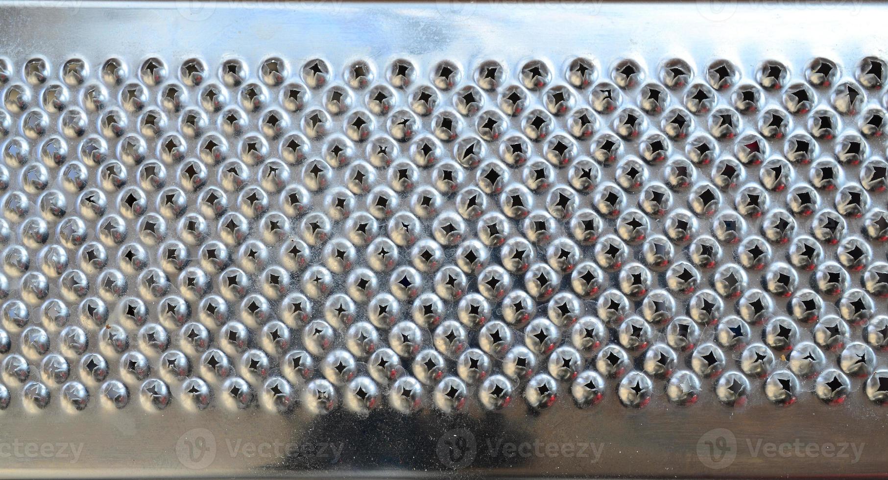 A fragment of a metal chrome grater close-up. Texture of blades for grinding food photo