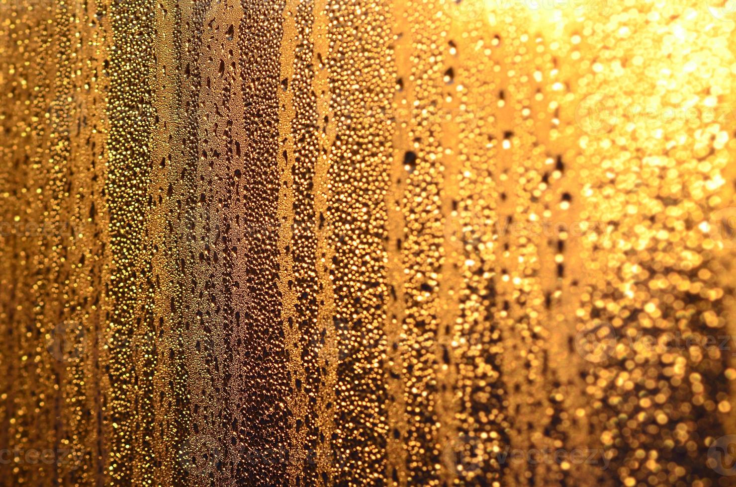The texture of misted glass with a lot of drops and drips of condensation against the sunlight at dawn. Background image photo