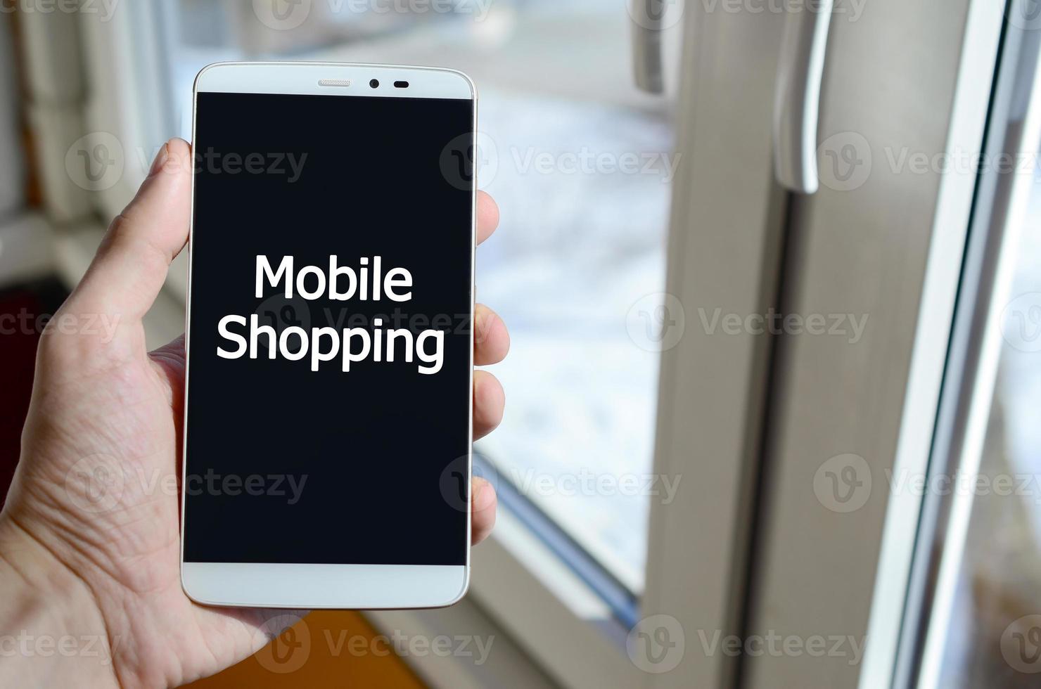 A person sees a white inscription on a black smartphone display that holds in his hand. Mobile shopping photo