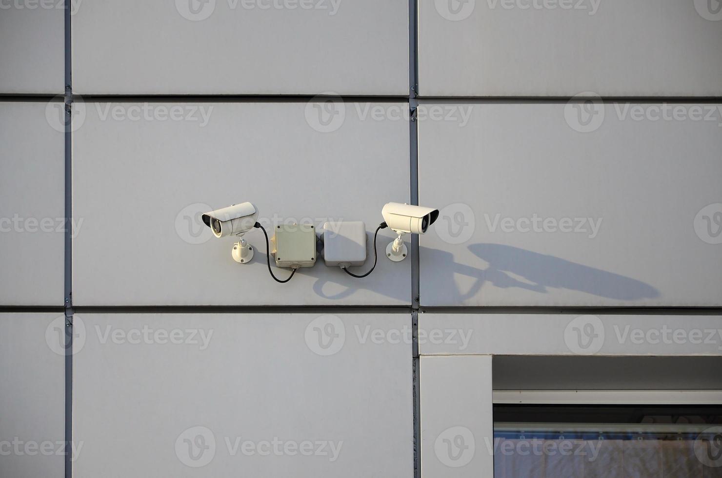 White surveillance camera built into the metal wall of the office building photo