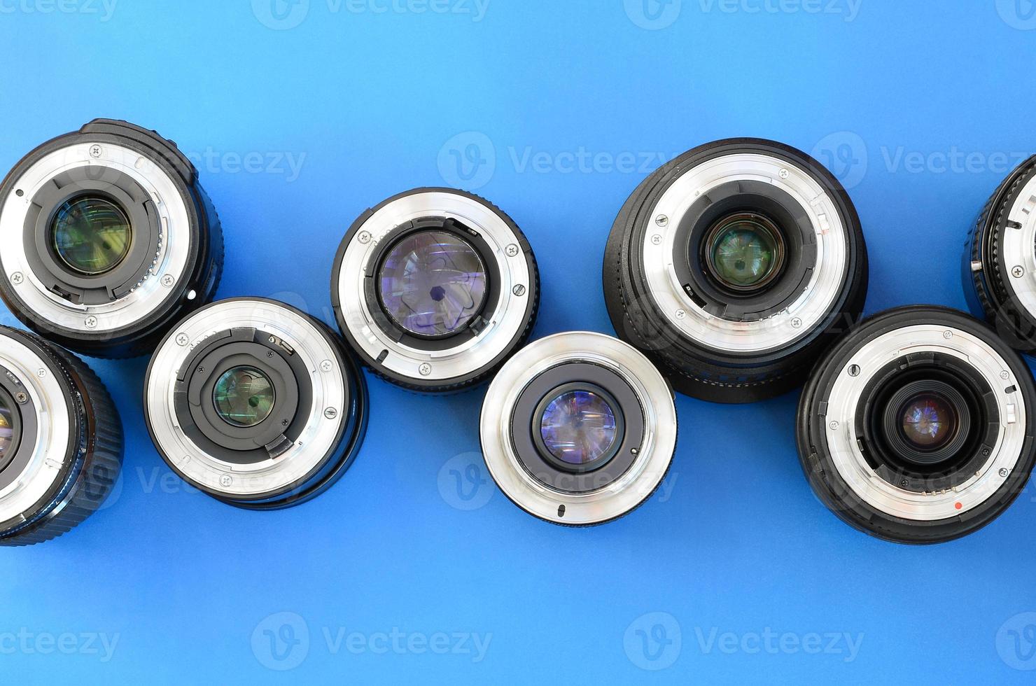 Several photographic lenses lie on a bright blue background. Space for text photo