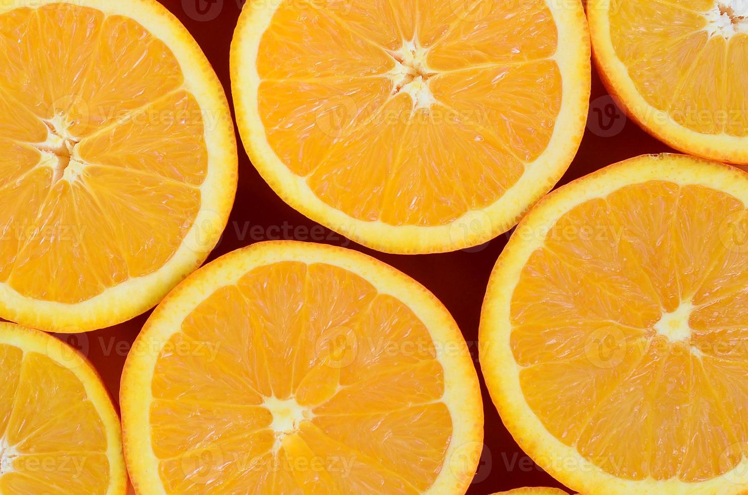 Top view of a several orange fruit slices on bright background in orange color. A saturated citrus texture image photo